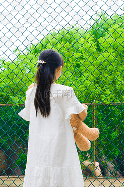 女生女孩抱玩具熊背影栅栏景色