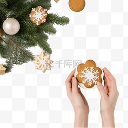 女手拿着饼干旁边的圣诞树枝和周