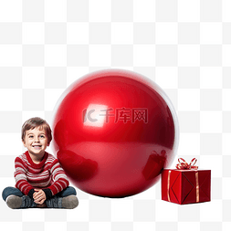 圣诞球红色图片_小男孩坐在礼物之间，手里拿着大