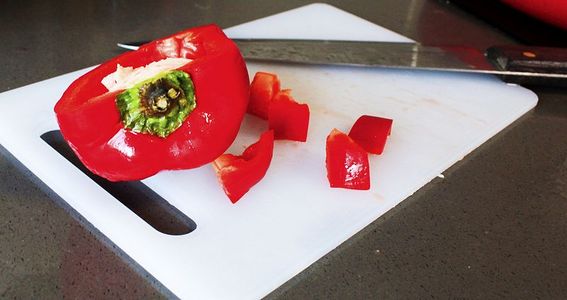 菜板上的红色菜椒和刀具
