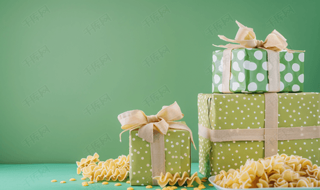 绿色背景中各种带蝴蝶结的礼盒和烤意大利面