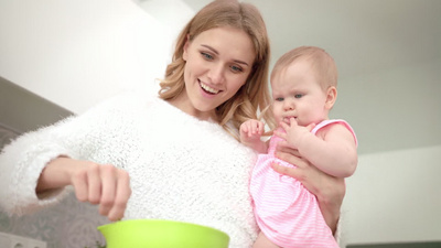 年轻的母亲手里抱着孩子做饭婴儿营养烹饪