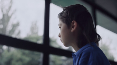 不高兴的小学生看着窗子坐在大厅里紧闭着男孩站起来离开霍尔
