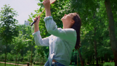 微笑的女人在公园里打羽毛球快乐的妈妈享受着积极的游戏