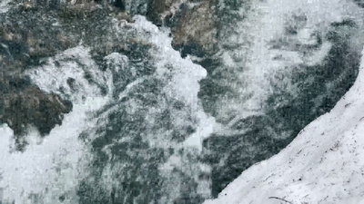冬日白雪中冒泡的小河特写冰冻湍急的河流河岸积雪