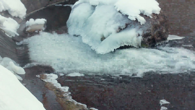 冰雪覆盖的石头冬天在石头附近流淌的水特写冬日河