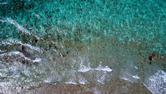 晶莹剔透的海浪冲击着海岸冲刷着澳大利亚鹅卵石般的琥珀色沙子