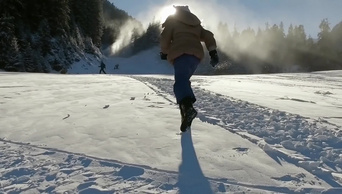 圣诞节穿着夹克戴着帽子的快乐女孩在美丽的雪地公园里玩耍和跑步在阳光的照耀下慢动作