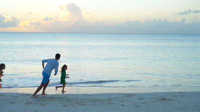 快乐的爸爸带着孩子在海滩上玩耍快乐的家庭在暑期海滩度假期间玩