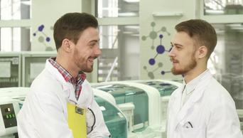 两名年轻的实验室技术人员站在实验室中央交谈
