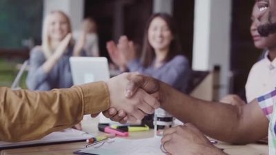 两个伙伴非洲和高加索商人握手一组人在办公室的背景拍手慢墨