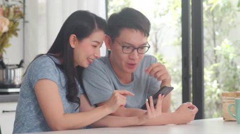 一对年轻的亚洲夫妇喜欢在家里用手机上网购物