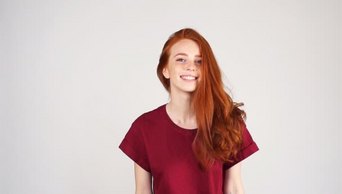漂亮开朗的红头发的女孩笑在相机上的白色背景在慢动作