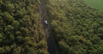 从上到下俯瞰无人驾驶飞机图像的汽车在公路上穿过树木和森林的山