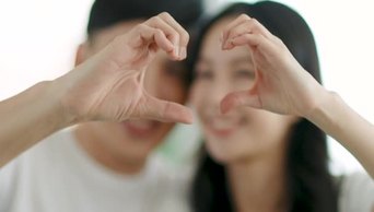 1080幸福的夫妻面容透过连在一起的手指塑造心形