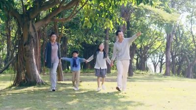 亚洲家庭一家四口父母与两个孩子手牵手走在公园里玩得开心