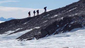 登山者攀登山与雪场。四个登山者登山