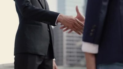 当天早晨亚洲商人和女商人站在一座大城市的一幢大写字楼附近一边