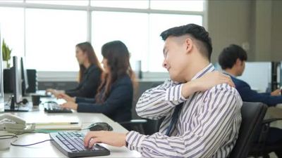 一位上班族由于长时间工作而面临严重的背痛并有患办公室综合症的