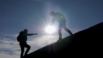 团队精神徒步旅行者互相帮助爬上高山