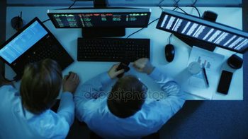 股票图片素材顶视图的两个股票经纪人寻找和分析市场数据在他们面前两个监视与