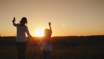 妈妈和女儿在日落时正在玩纸飞机