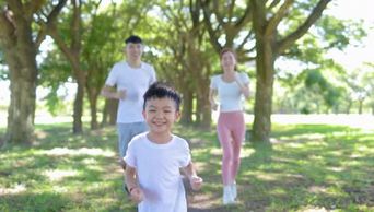 快乐男孩与父母在城市公园慢跑
