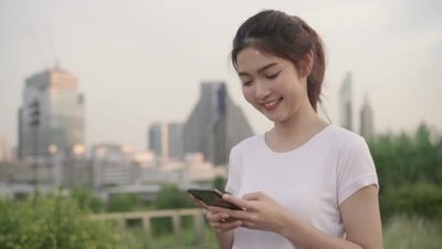 一个美丽的女人在街道上散步玩手机4K