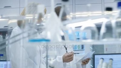男性和女性首席科学家步行穿过现代实验室讨论未来的可能性计算机