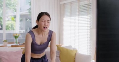 运动健身实拍视频素材1080年轻活跃的亚洲女人笑着在舒适的家里在电视上看完网上体
