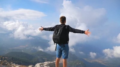 旅游实拍视频素材徒步旅行者背着背包站在山边举起双手享受自由