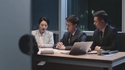 由亚洲商人组成的团队工作到很晚的男人和女人晚上在办公室开会