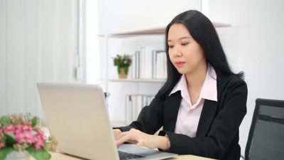 使用笔记本电脑键盘打字的亚洲女商业女性专业用户坐在写字台前与
