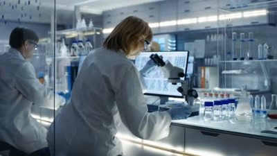 她的电脑及材料在显微镜下看高级女生物学家工程她是在一个现代的