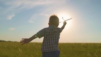 快乐的孩子，男孩，在阳光下奔跑，在夏天的田野里玩着玩具飞机
