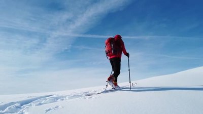 4K滑雪登山者爬上蓝天之上的雪山徒步